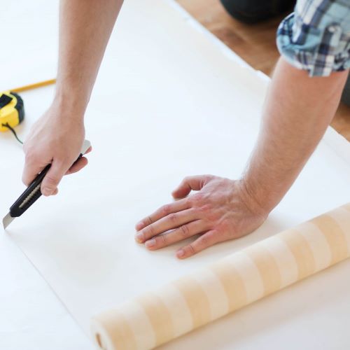 découpe de tapisserie au cutter sur table de tapissier