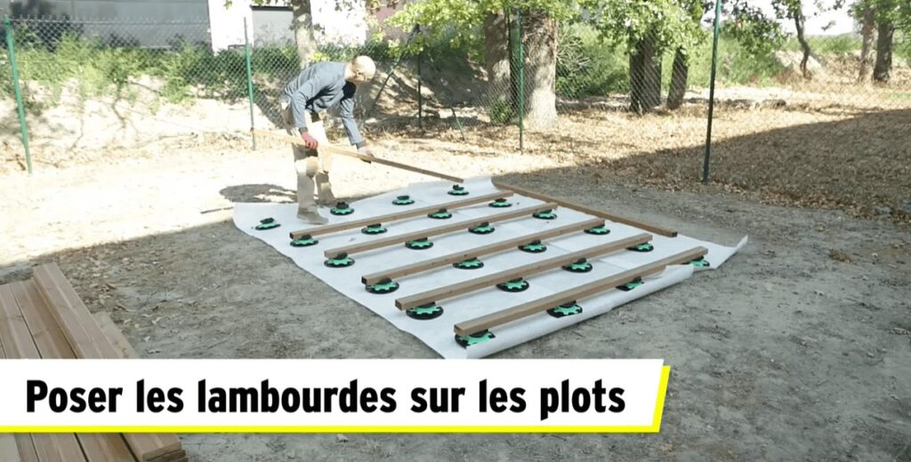 un homme pose des lambourdes sur des plots de terrasse pvc